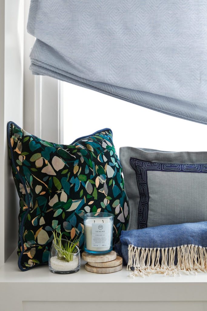 A peaceful seat with a candle and blue pillows. Posted on A Zen-Filled Checklist to Declutter Your Home by Deborah Silver Design. 